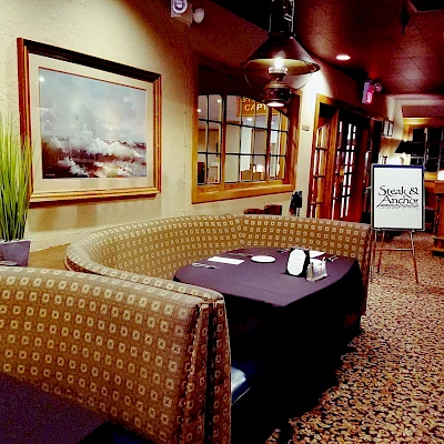 A cozy restaurant interior with patterned booths, a painting on the wall, and a stand displaying "Specials & Announcements," featuring a warm ambiance.