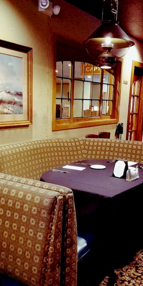 A cozy restaurant interior with patterned booths, a painting on the wall, and a stand displaying "Specials & Announcements," featuring a warm ambiance.